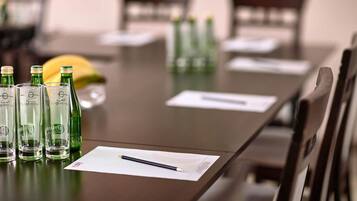 Una mesa de conferencias con botellas verdes, un plátano y un cuaderno con un bolígrafo.