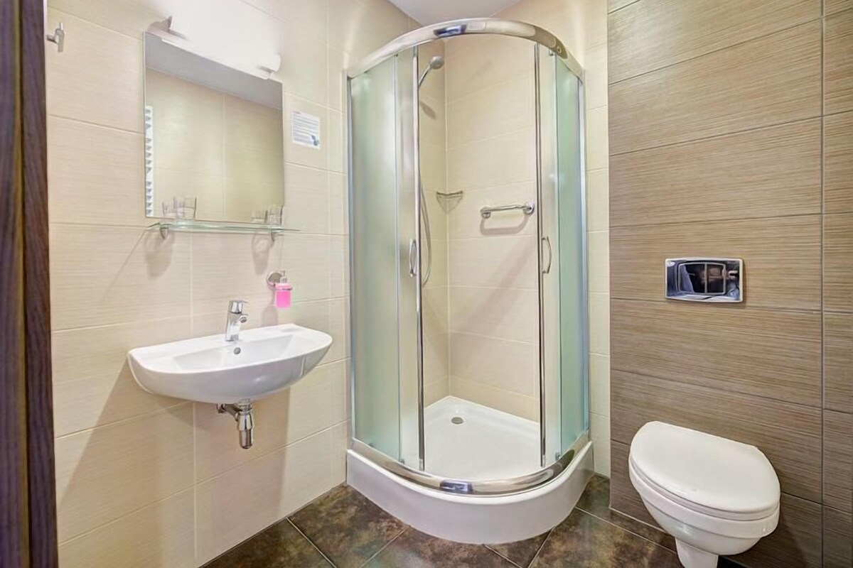Un baño con ducha de vidrio, lavamanos e inodoro.