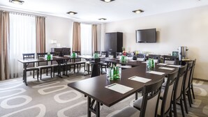 Une salle de conférence équipée d’une longue table, de chaises, d’un téléviseur à écran plat et d’un meuble de rangement.