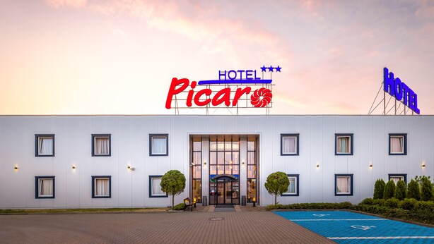 Un hôtel appelé « Picaro », doté d’une façade moderne, de grandes fenêtres et d’un parking bleu.