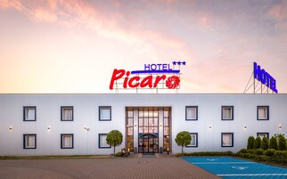 Un hotel llamado "Picaro" con una fachada moderna, ventanas amplias y un estacionamiento azul.
