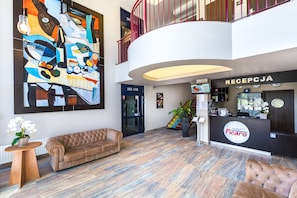 A hotel lobby with a large abstract painting, a reception desk, and a staircase.