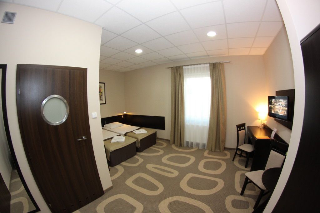 Une chambre d’hôtel équipée d’un lit, d’un bureau, d’une chaise, d’une télévision et d’une fenêtre avec des rideaux.