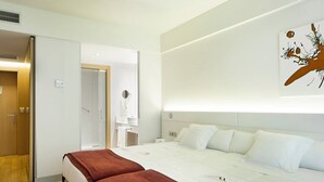 Habitación de hotel con una cama grande, armario, baño y una obra de arte colgada en la pared.