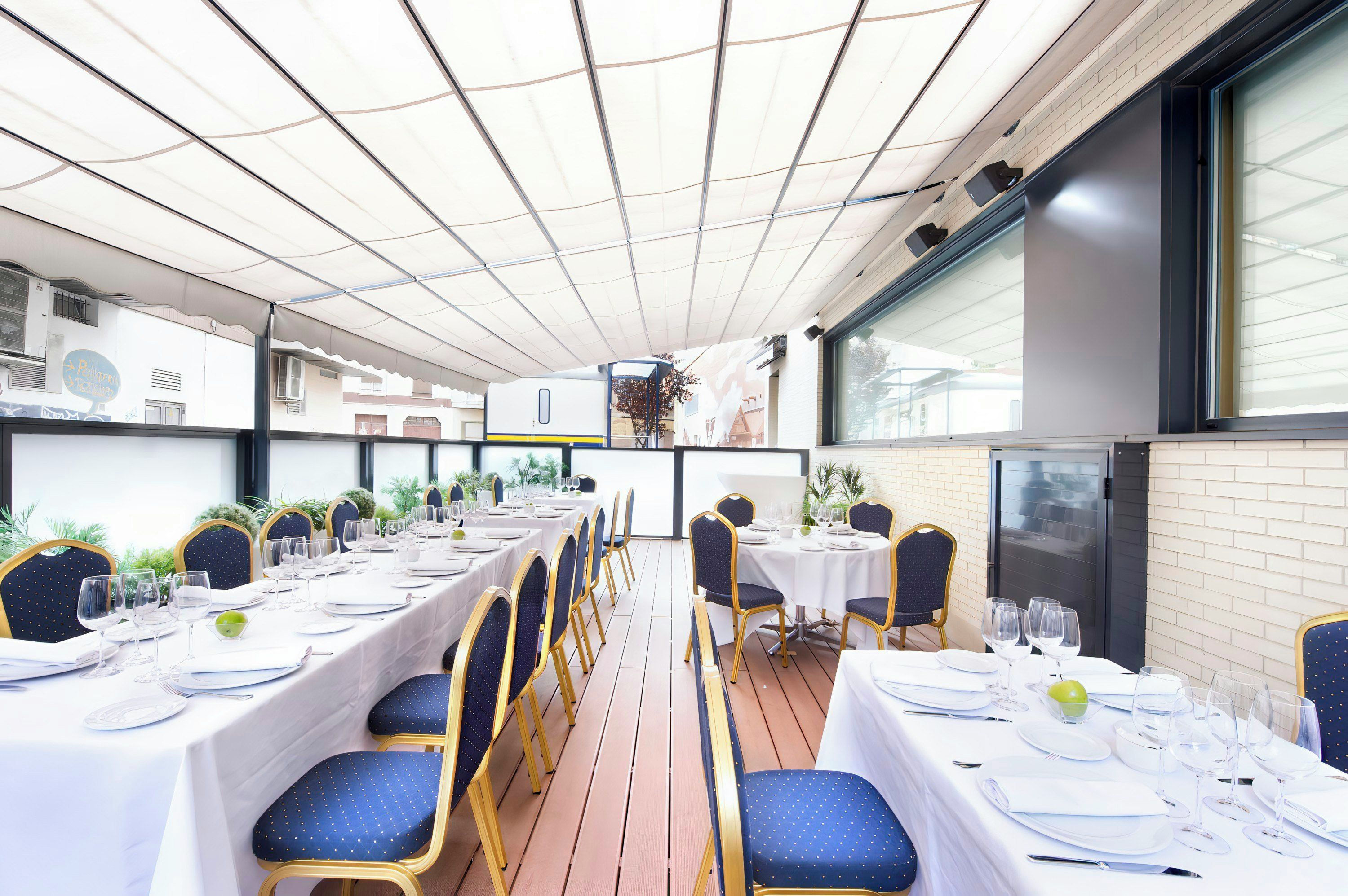 Een restaurant met meerdere eettafels, uitgevoerd in modern design met een betegelde plafond en uitzicht op de stad.