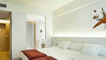 Ein Hotelzimmer mit einem Bett, einem Nachttisch, einem Spiegel und einem an der Wand hängenden Kunstwerk.