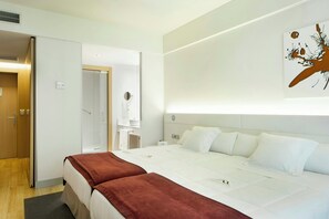 Une chambre d’hôtel comprenant un lit, une table de chevet, un miroir et une œuvre d’art accrochée au mur.