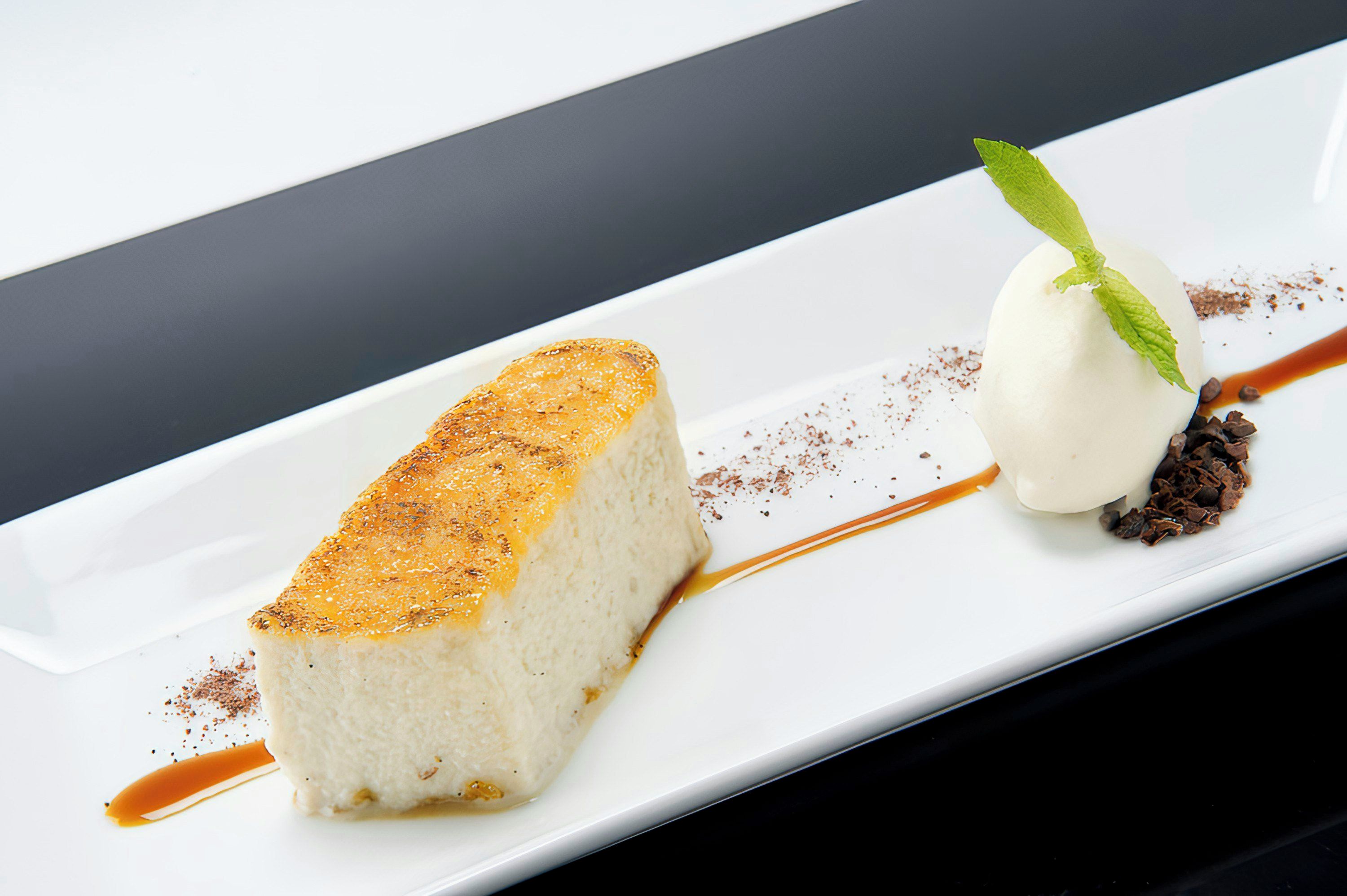 A dessert plate with a slice of cake and a scoop of ice cream, both garnished with chocolate shavings.