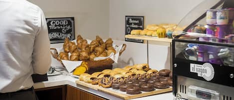 Un bufé de desayuno con diversos pasteles y una máquina de café.