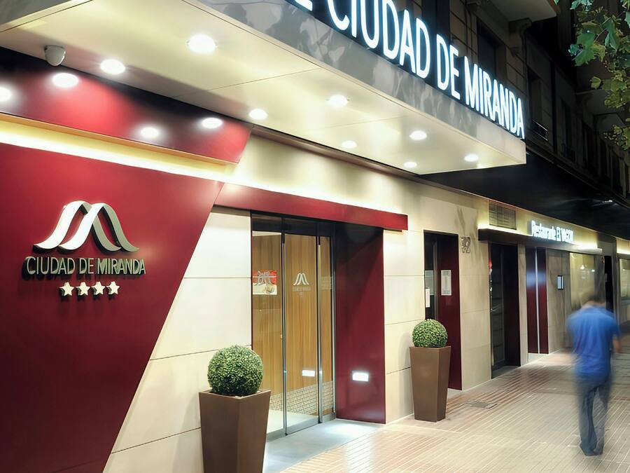Ein Hotel Eingang mit einem Schild, auf dem 'HOTEL CIUDAD DE MIRANDA' steht, und einem Logo mit fünf Sternen.