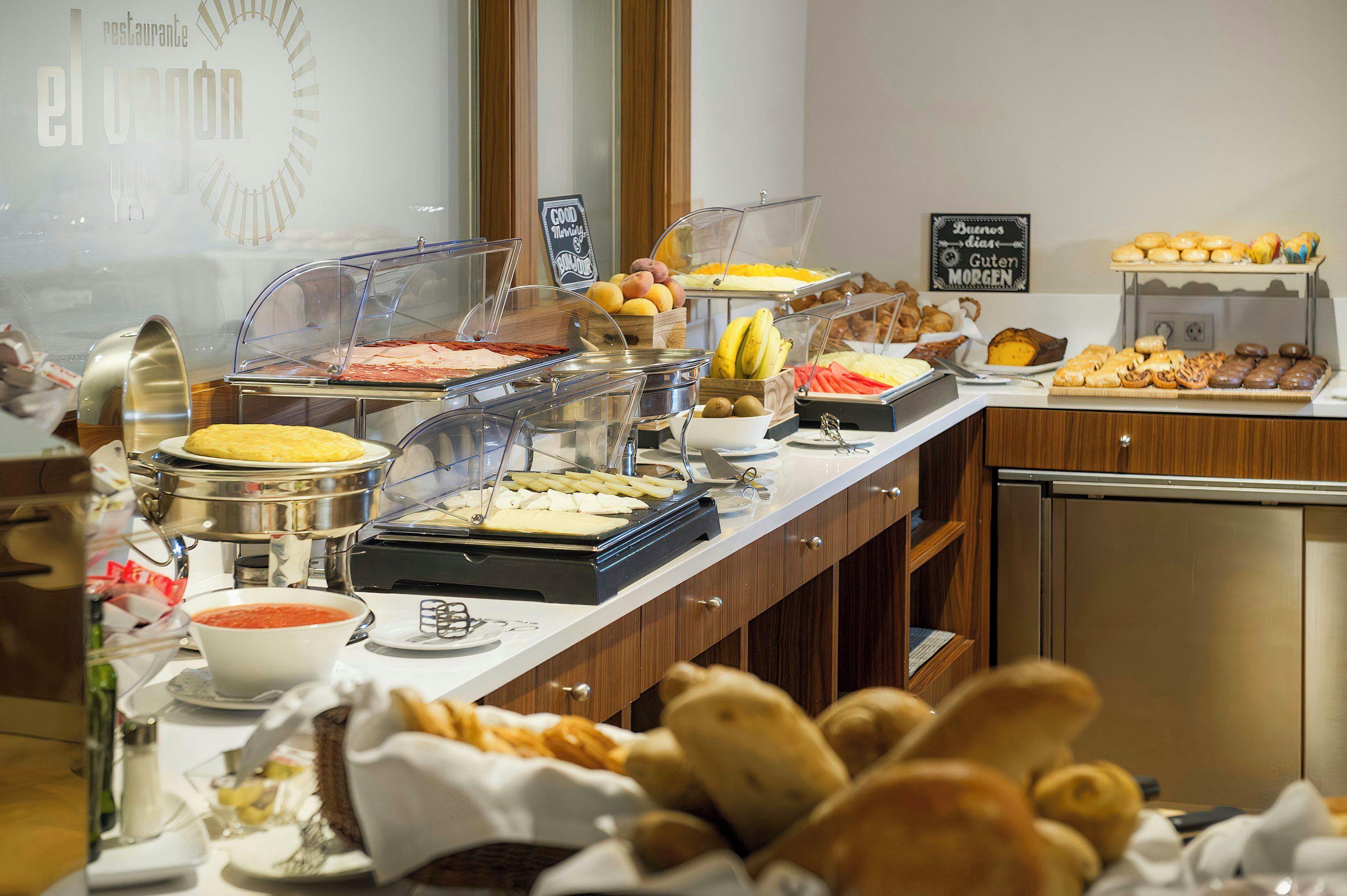 Un buffet proposant une variété de plats, notamment des fruits, des pâtisseries et un assortiment de fromages.