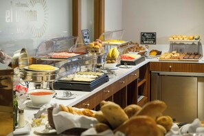 Un buffet proposant une variété de plats, notamment des fruits, des pâtisseries et un assortiment de fromages.