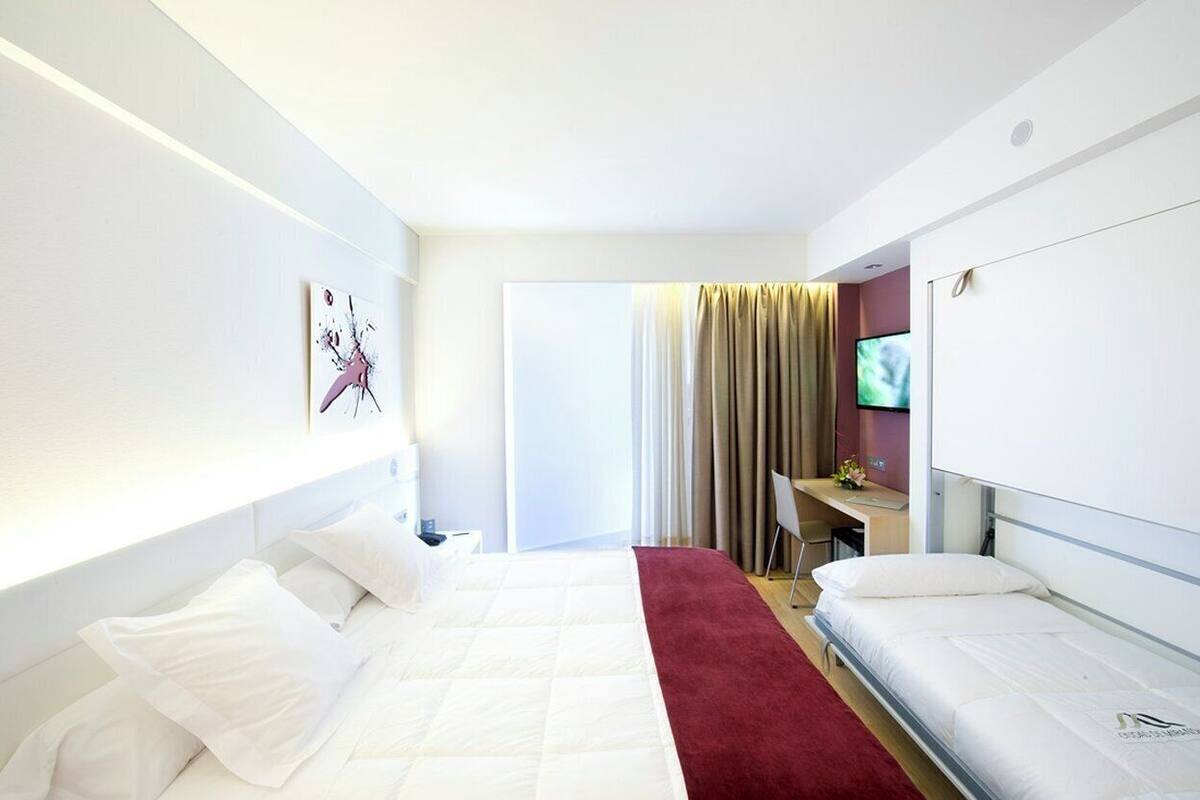 A modern hotel room with a large bed, a desk, and a television.