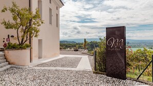 L’entrée d’un hôtel, avec un chemin de pierre menant à un bâtiment, une enseigne et une vue sur la campagne.