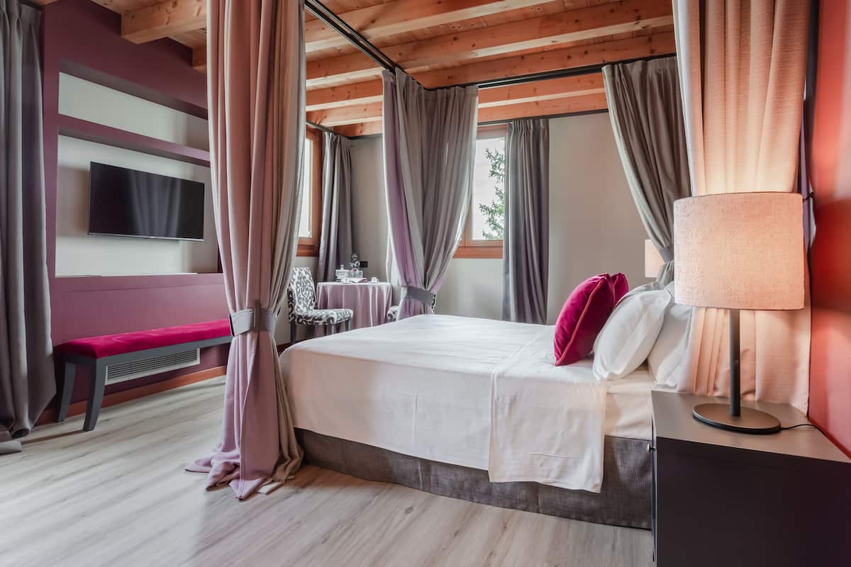 Un dormitorio con cama, mesita de noche, lámpara y cortinas.