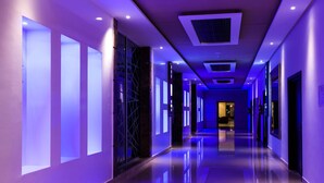 Een moderne hotelgang met glanzende vloeren, inbouwverlichting en grote ramen.