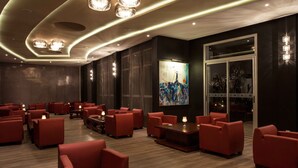 Een moderne hotellobby met rode zitplaatsen, een groot abstract schilderij en een glazen ingang.