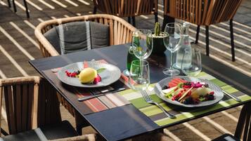 A dining table with plates of fruit, wine glasses, and a bottle of wine.
