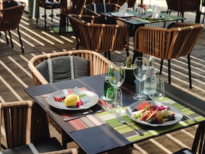 Une table à manger avec des assiettes de fruits, des verres à vin et une bouteille de vin.