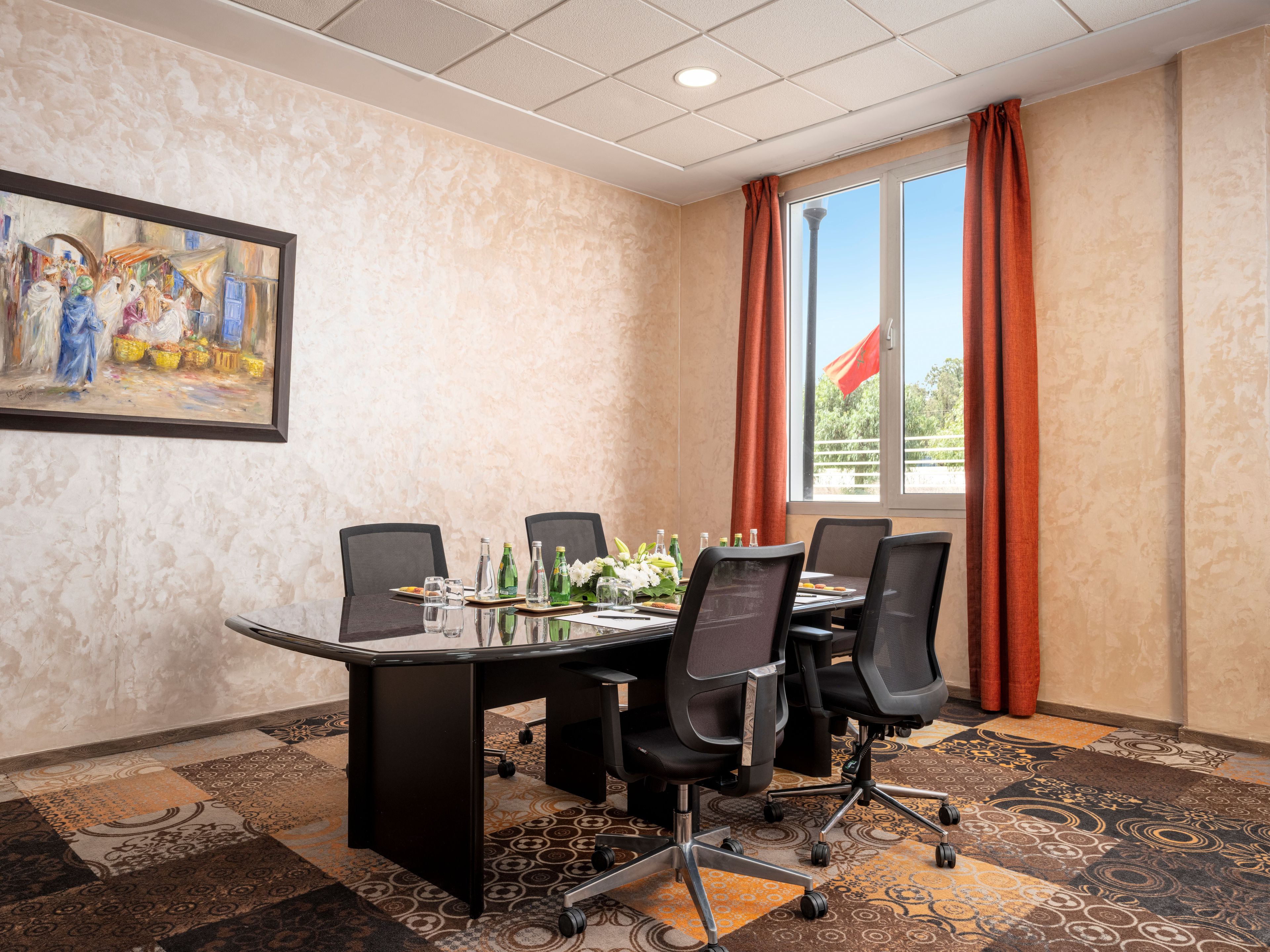 A conference room with a table, chairs, and a painting on the wall.