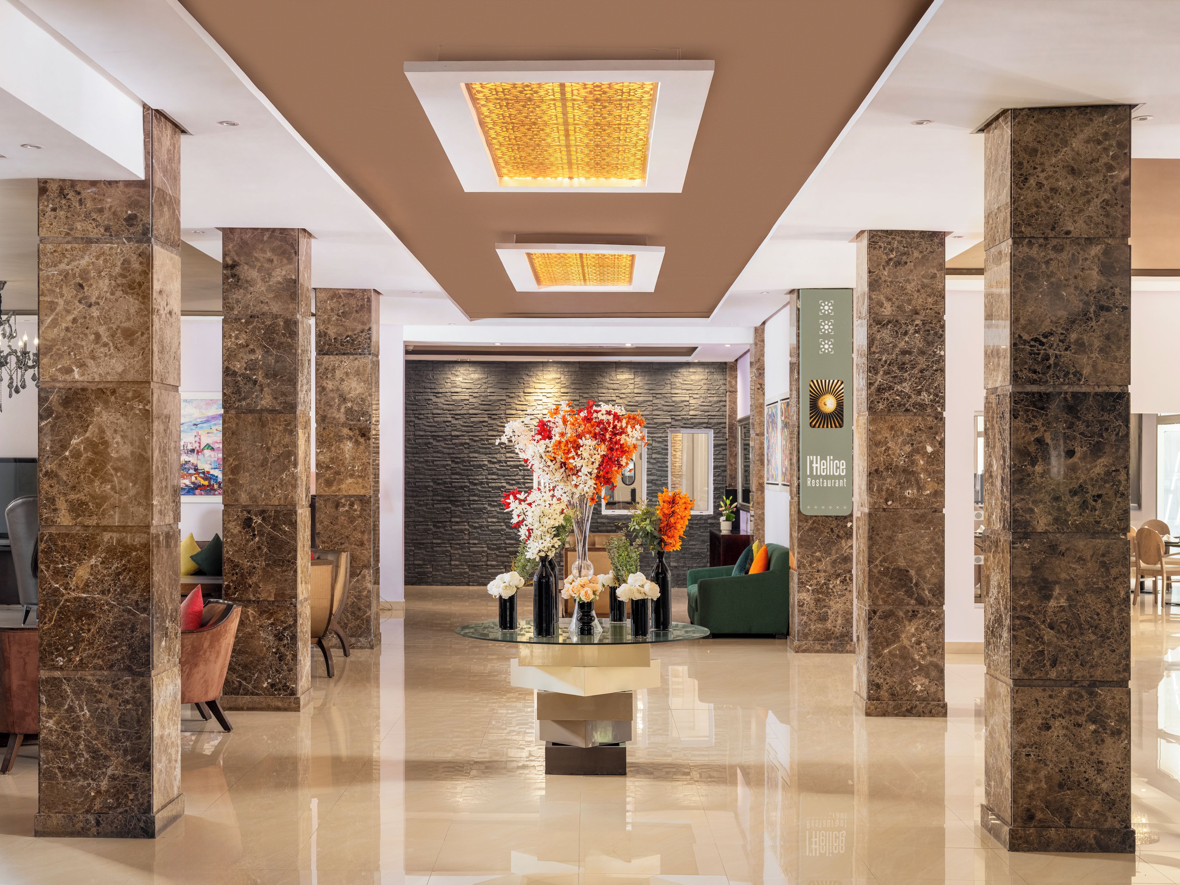A modern lobby with marble columns, a reception desk, and a decorative floral arrangement.