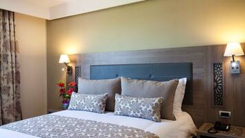 A hotel room with a large bed, two bedside lamps, a nightstand with a phone, and a decorative wall panel.