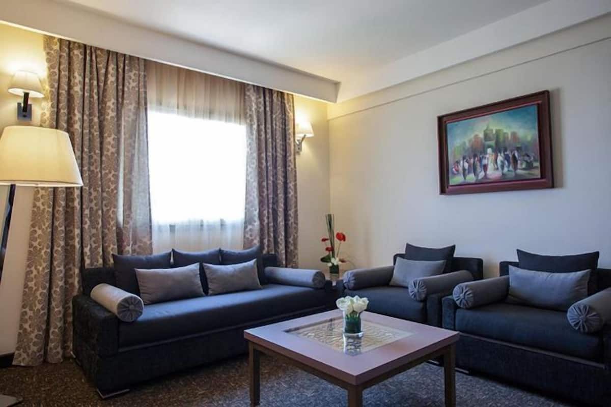 A living room with two dark sofas, a coffee table, and a painting on the wall.