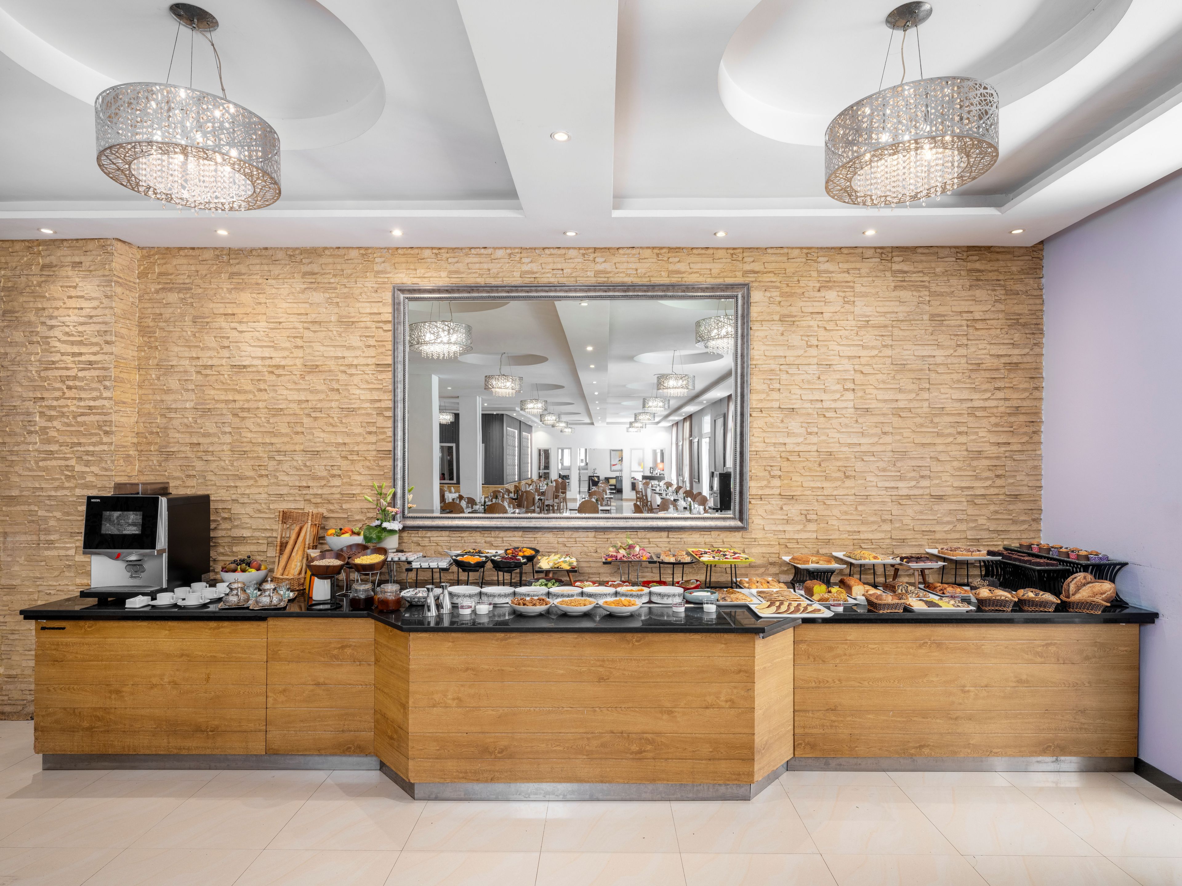 Un comptoir de buffet proposant une variété de plats, une machine à café et un grand miroir au mur.