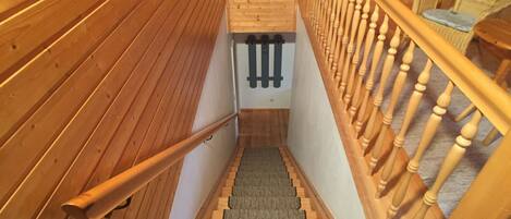 A wooden staircase with a carpeted landing and a wooden railing.