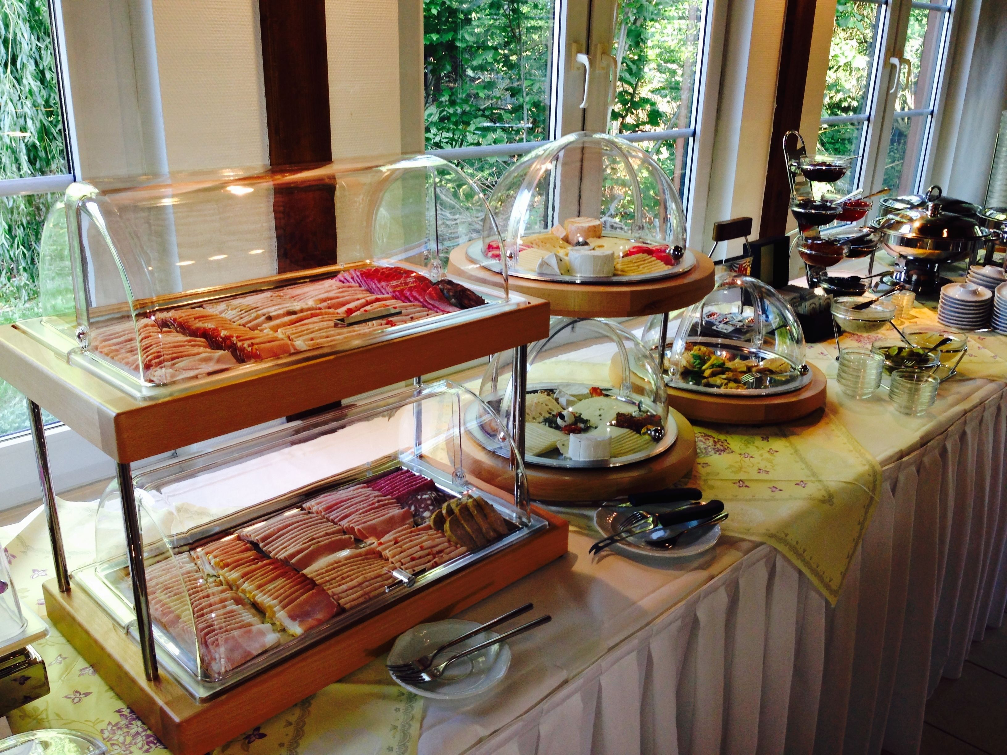 Een buffet met diverse soorten eten, gepresenteerd in glazen vitrines en op serveerplanken.