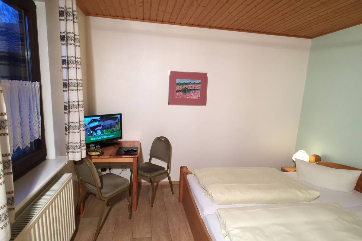 Une chambre d’hôtel avec un bureau en bois, une télévision, une chaise et deux lits.