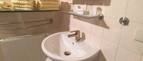A bathroom with a white sink, a mirror, and a towel rack.
