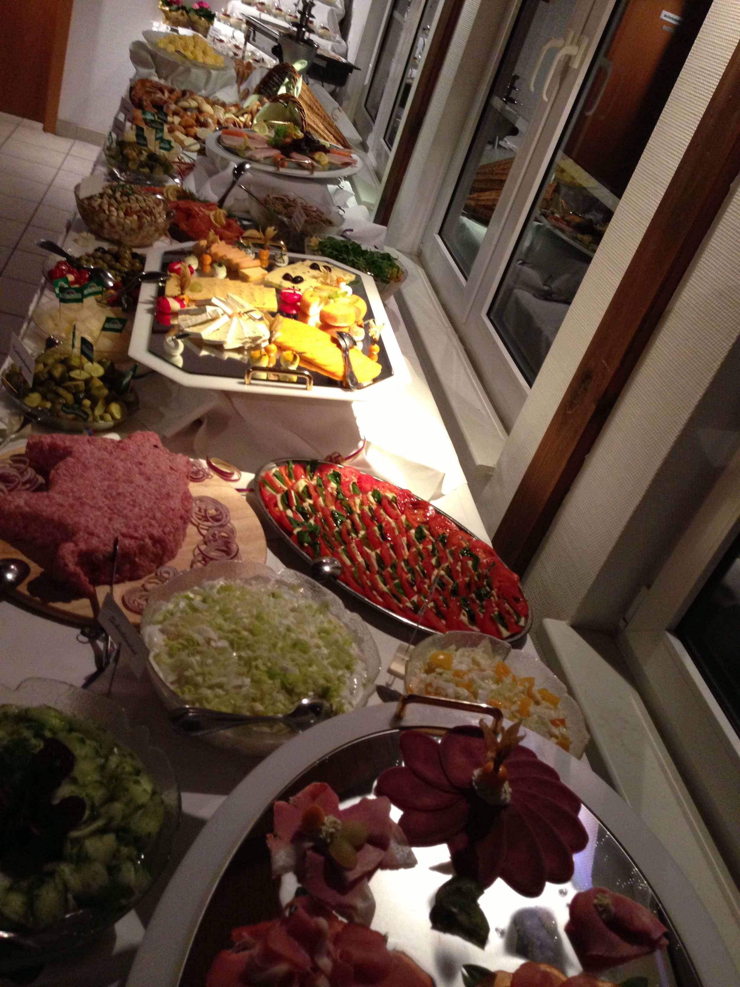 Un bufé con diferentes opciones de comida, incluyendo ensaladas, carnes y quesos.