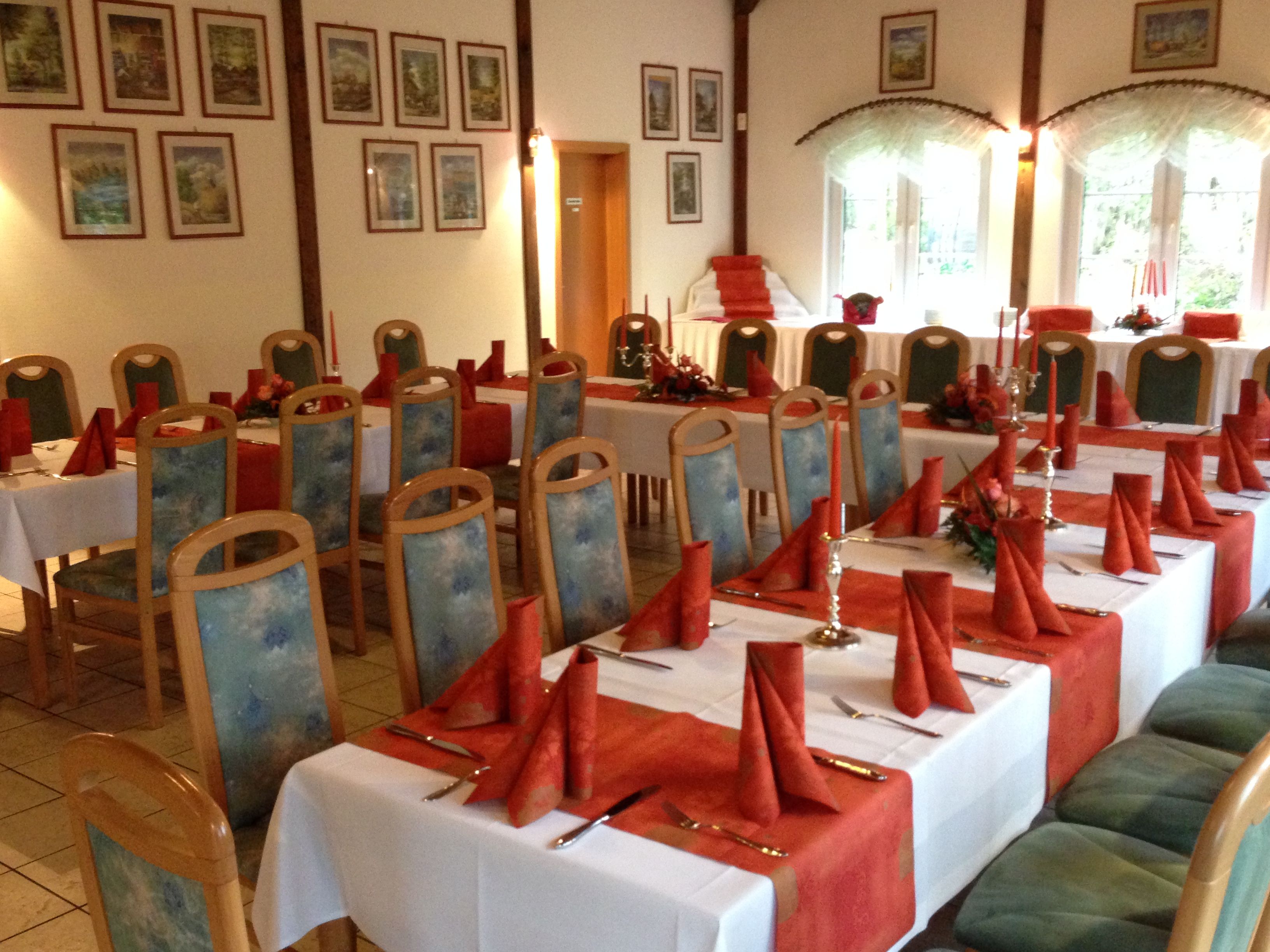 A dining area with tables set for a meal, chairs with blue upholstered seats, and framed pictures on the walls.