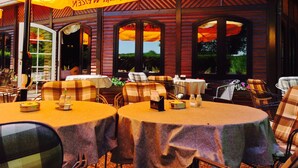 Un espace de restauration en plein air avec des tables protégées par des parasols jaunes, agrémenté d’une nappe à carreaux et de chaises en métal.