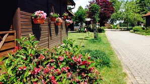 Un bâtiment en bois, avec des jardinières sur le côté, une allée pavée et une zone herbeuse plantée.