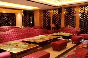 A room with red upholstered seating, multiple tables, and a patterned wall design. - Xiongsen Holiday Villa (Chenzhou)