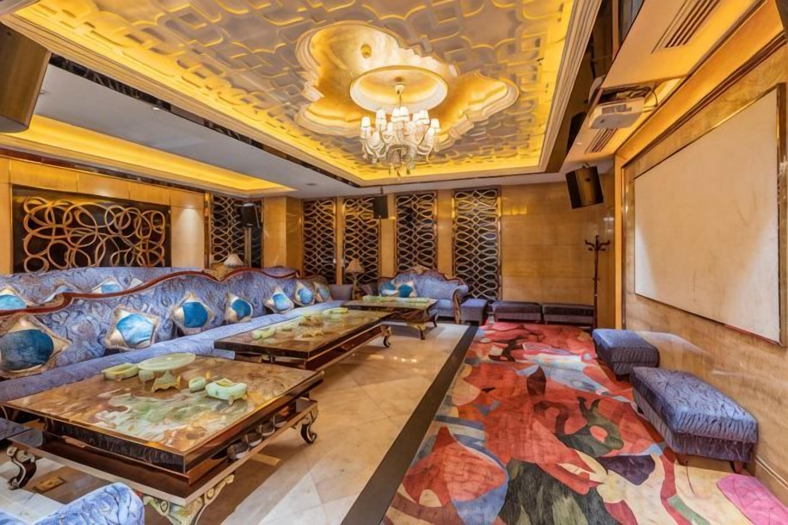 A luxurious hotel lobby with a grand chandelier, plush seating, and ornate decor.