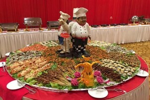 A buffet table with a variety of food items and two chef figurines.