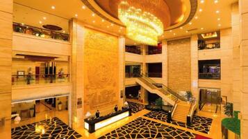 A spacious lobby with a central staircase, a reception desk, and a decorative wall.