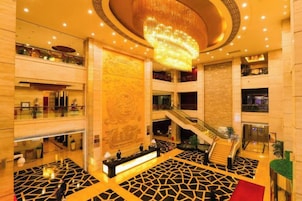 Eine großzügige Lobby mit einer zentralen Treppe, einem Empfangsbereich und einer dekorativen Wand.