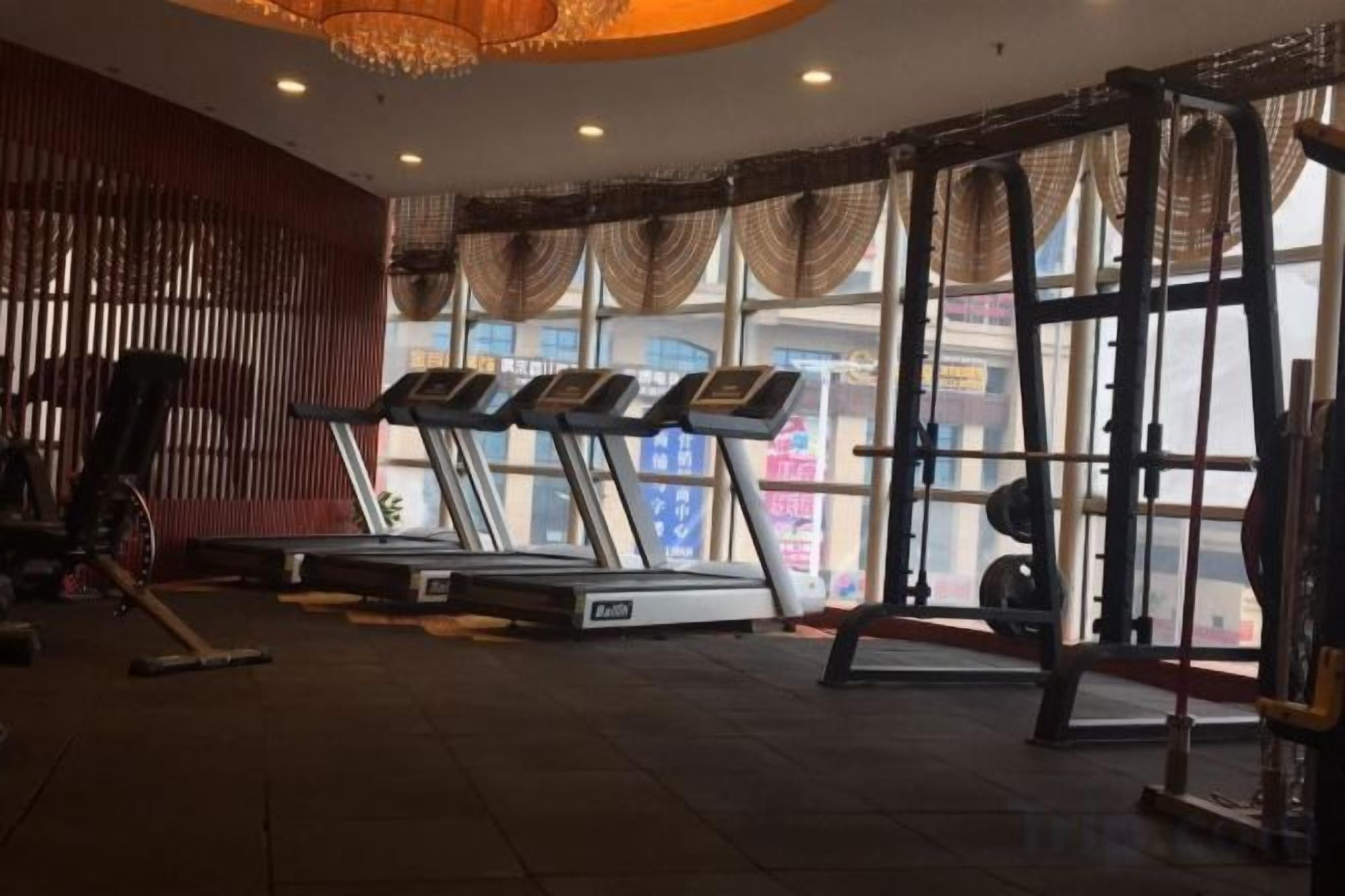 Ett gym med löpband, en ställning för knäböj och en viktbänk.