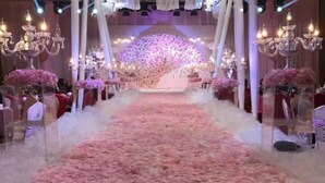 A wedding venue with a floral carpet leading to a stage, chandeliers, and red chairs. - Xiongsen Holiday Villa (Chenzhou)