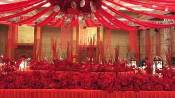 Un salón de banquetes con mantel rojo, cortinas rojas colgantes y arreglos florales.