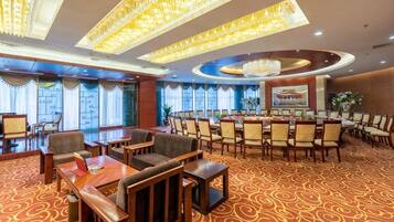A hotel conference room with round tables, chairs, and a carpeted floor.