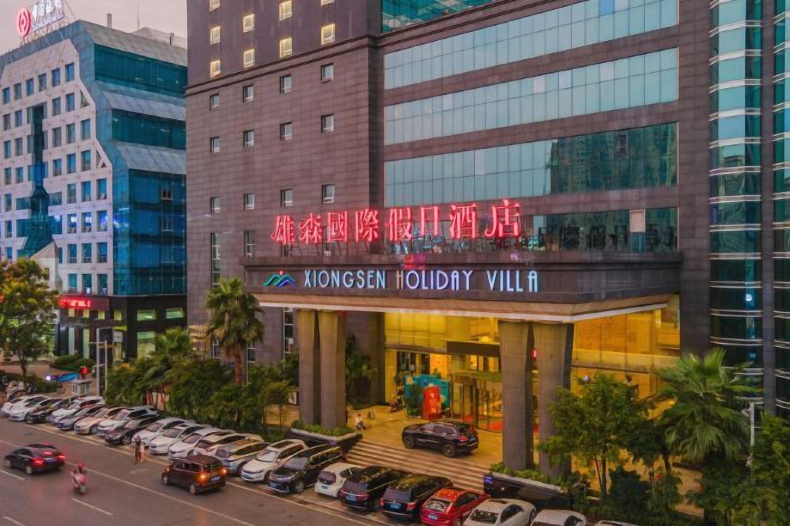 A hotel with a modern facade, a visible entrance, and a parking lot with several cars.
