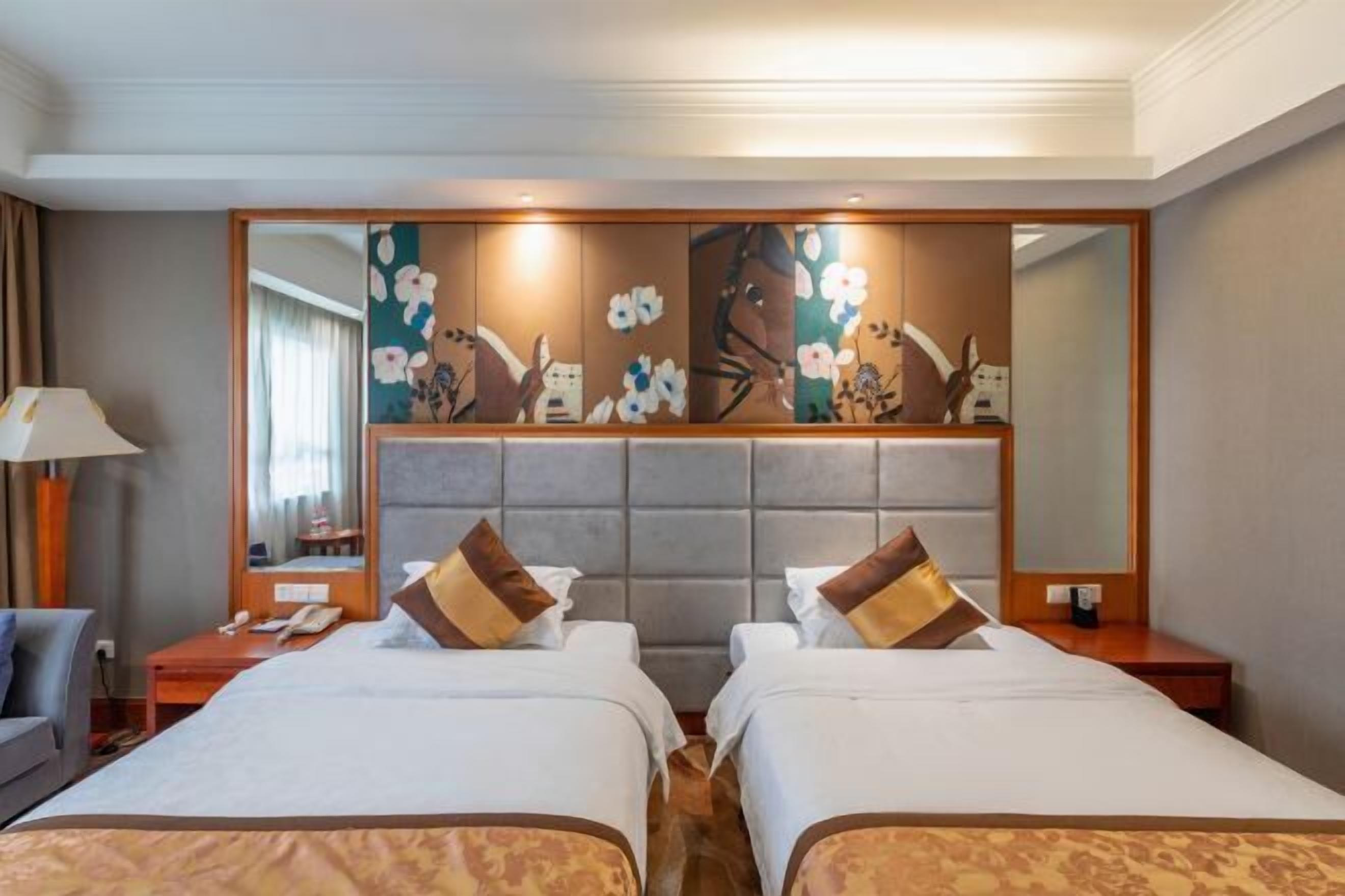 A hotel room with two beds, a large mirror, and a decorative wall panel.