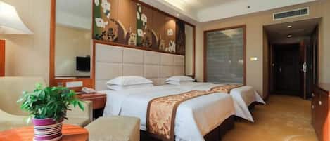 A hotel room with a large bed, a desk, a chair, a potted plant, and a large mirror.