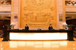 A reception desk with three staff members, a large decorative wall, and a polished floor.