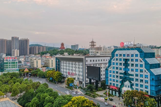 A cityscape with modern buildings, a pagoda, and a large blue structure with a sign.
